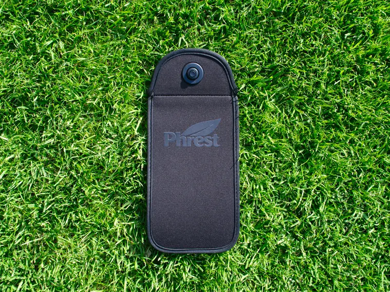Schwarze Phrest-Hülle aus Neopren mit eingeprägtem Logo, von oben auf Rasen fotografiert
